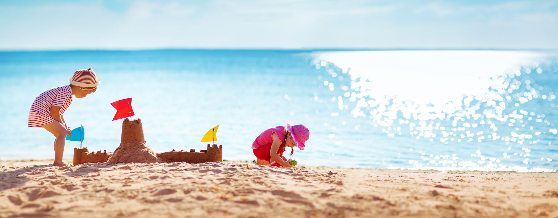 Boy and girl playing on the beach on summer holidays. Children building a sandcastle at sea