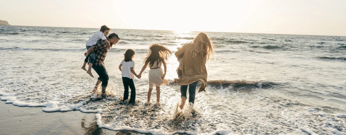 Family running into the ocean and sunset