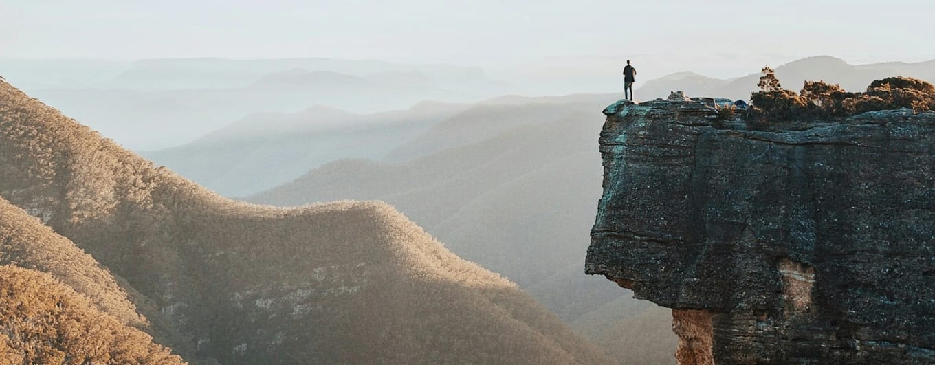 Travel image of man standing on a cliff with panoramic view