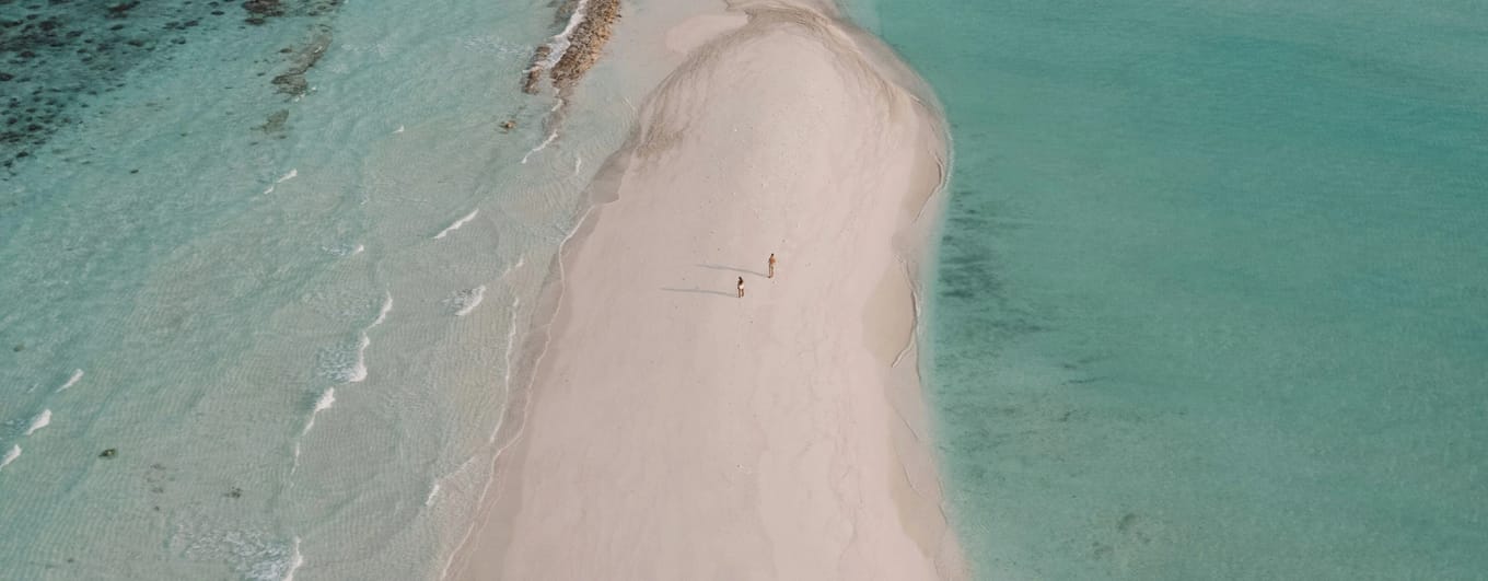 Aerial view of sandbank and two people walking on it