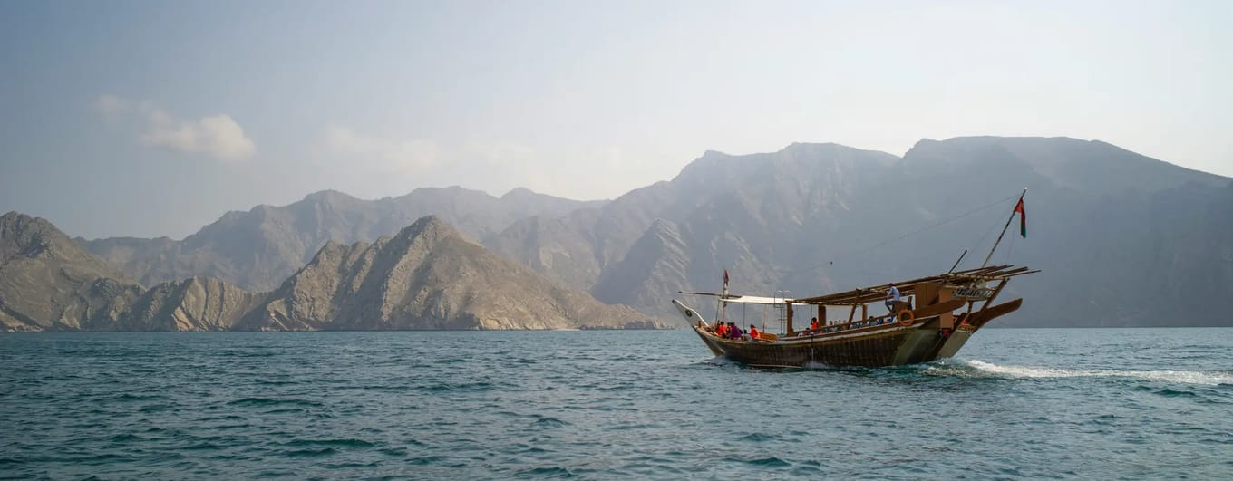 Dhow boat sailing with mountainous landscape