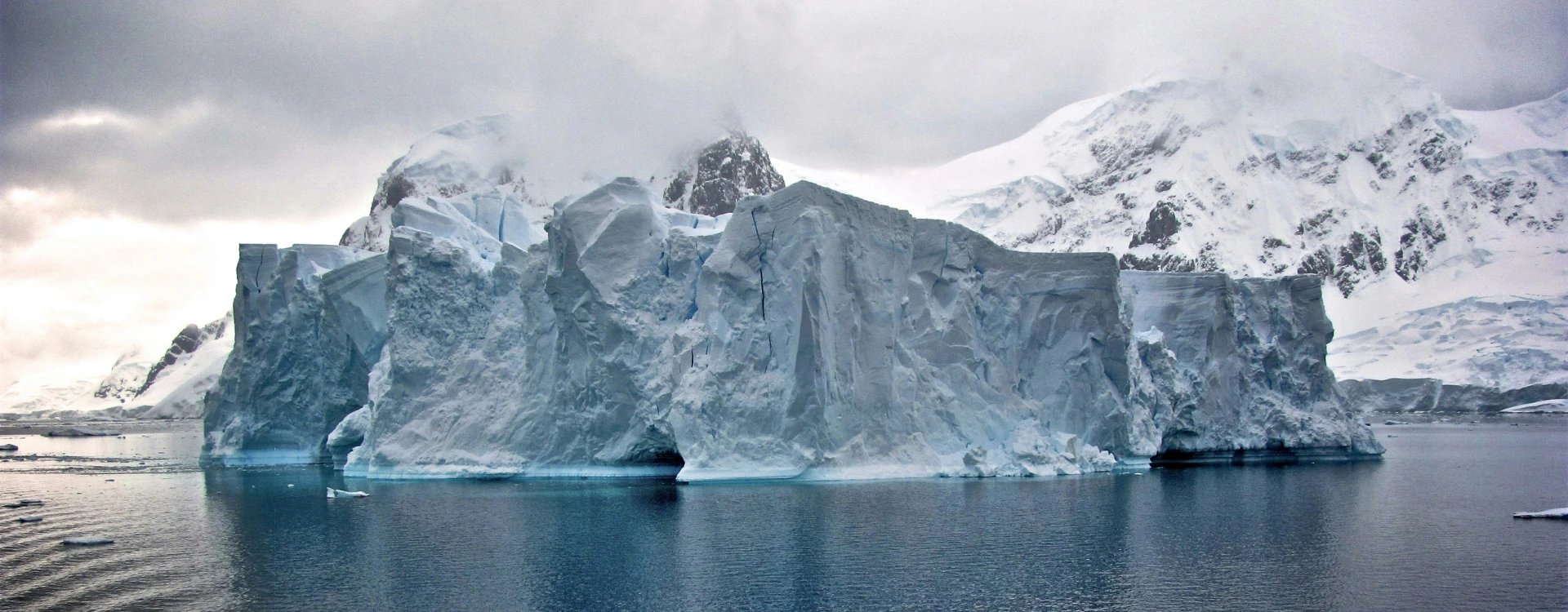 view of a large iceberg with cloudy skies