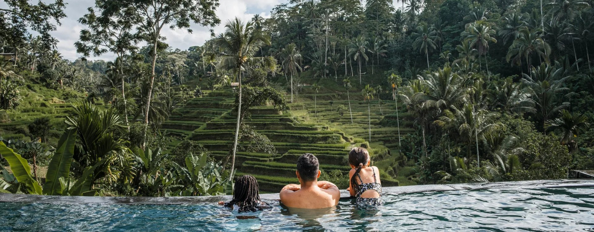 family in an infinite pool in bali overlooking a rice paddy