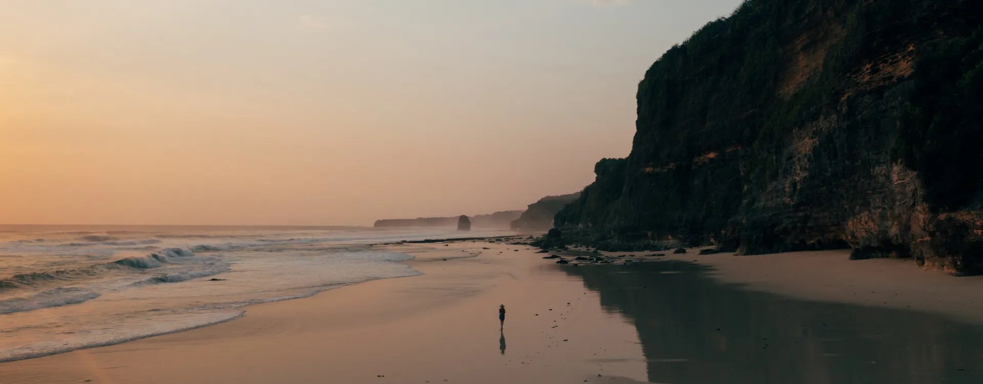 woman walking on a beach at sunset in indonesia