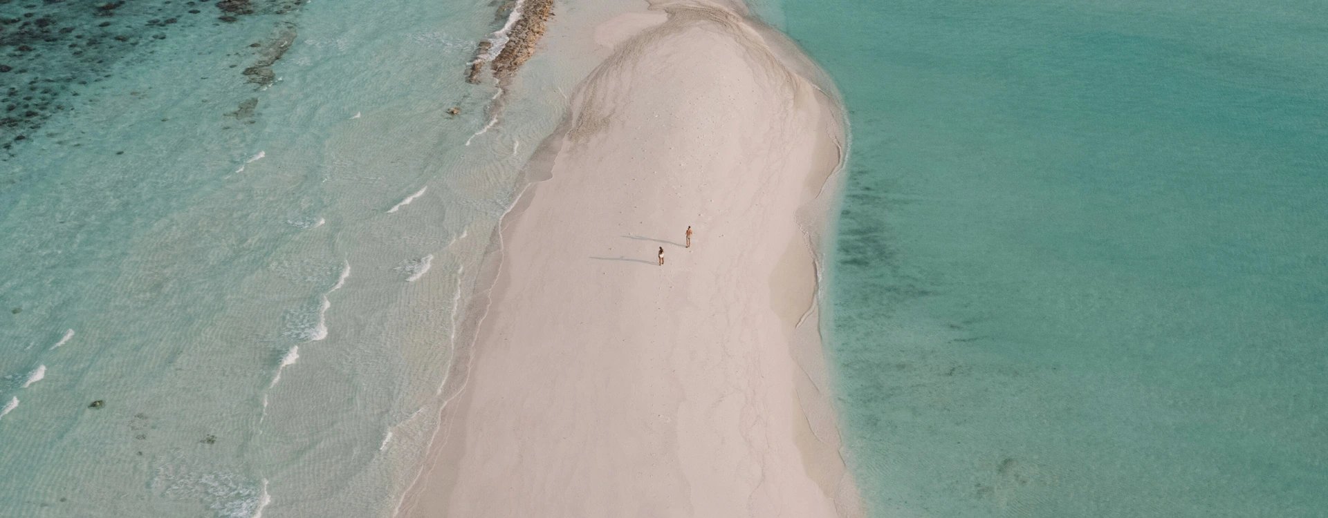 Aerial view of sandbank and two people walking on it