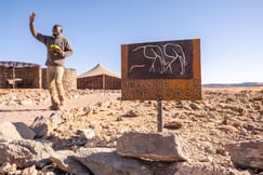 Welcome sign with man welcoming at Camp Doros