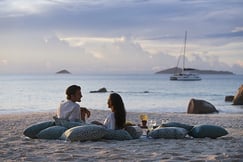 Couple enjoying sundown on the beach at Raffles Praslin, Seychelles