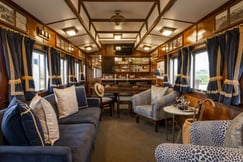 Railway carriage living area with sofas, chair and a bar