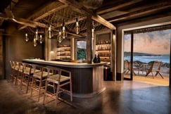 Bar with bar stools and view onto terrace and the ocean in distance