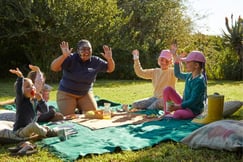 Children playing outside with a team leader on a blanket