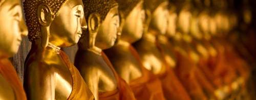 Buddha statues with orange robes in a row at Wat Arun, Bangkok Thailand