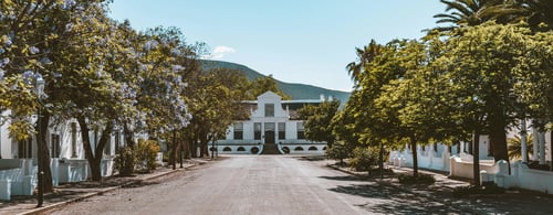 View of old colonial white house in tree lined street in South Africa