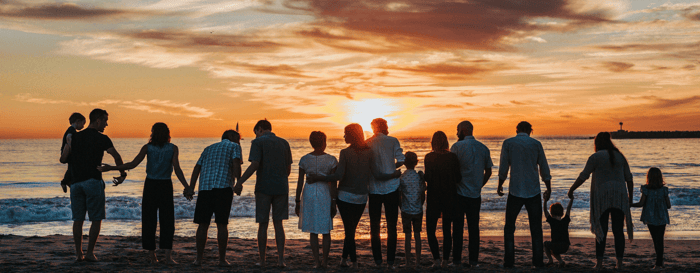  ? Family holding hands on the beach looking out to the sunset 