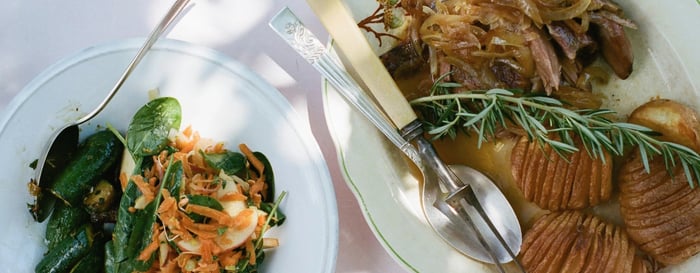 Close up of two plates of food, salad, and meat with potatoes