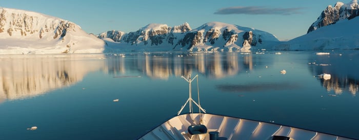 Bow of a boat with icebergs in the distance