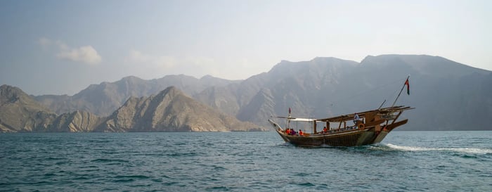 Dhow boat sailing with mountainous landscape